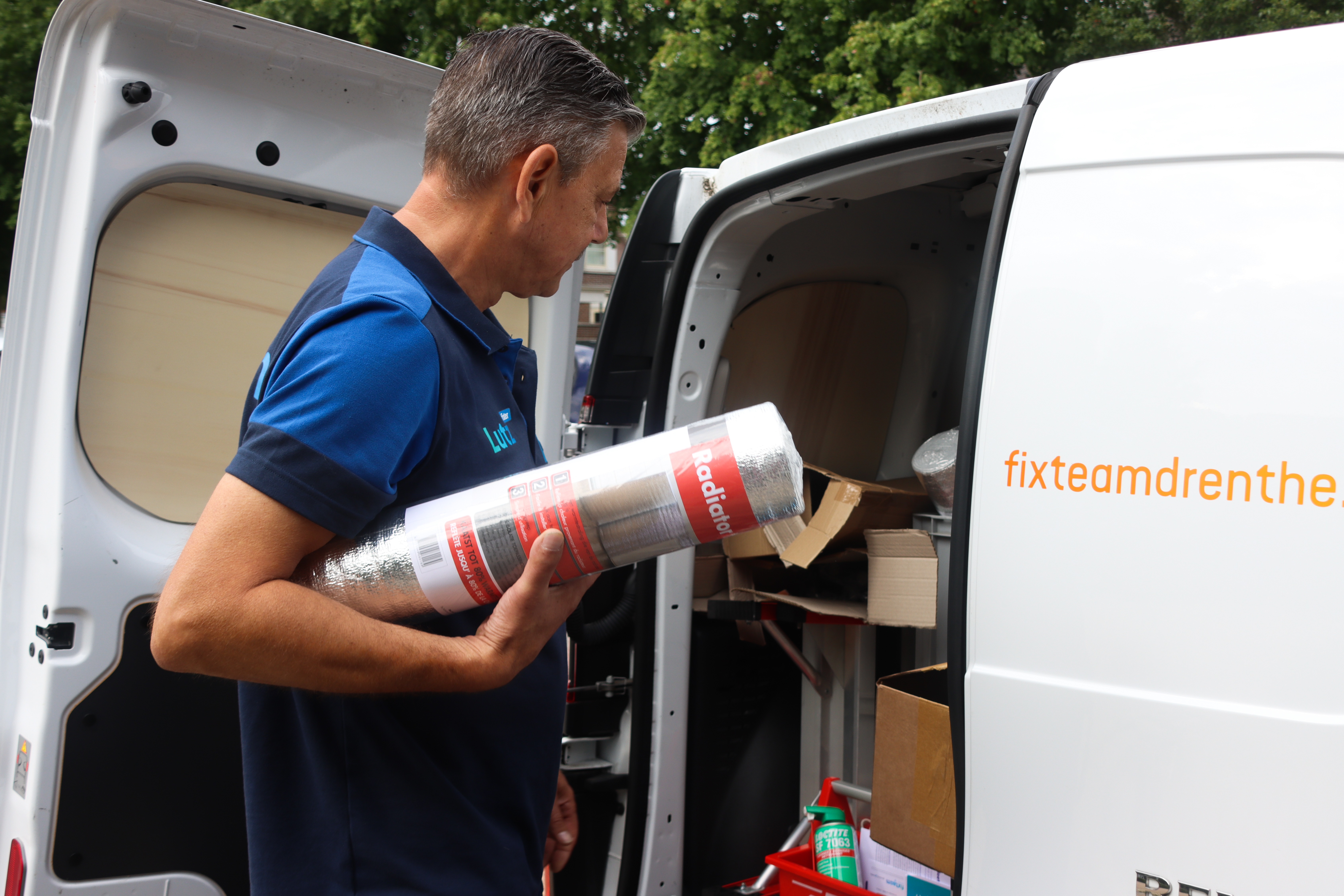 Man bij auto met rol radiatorfolie onder zijn arm