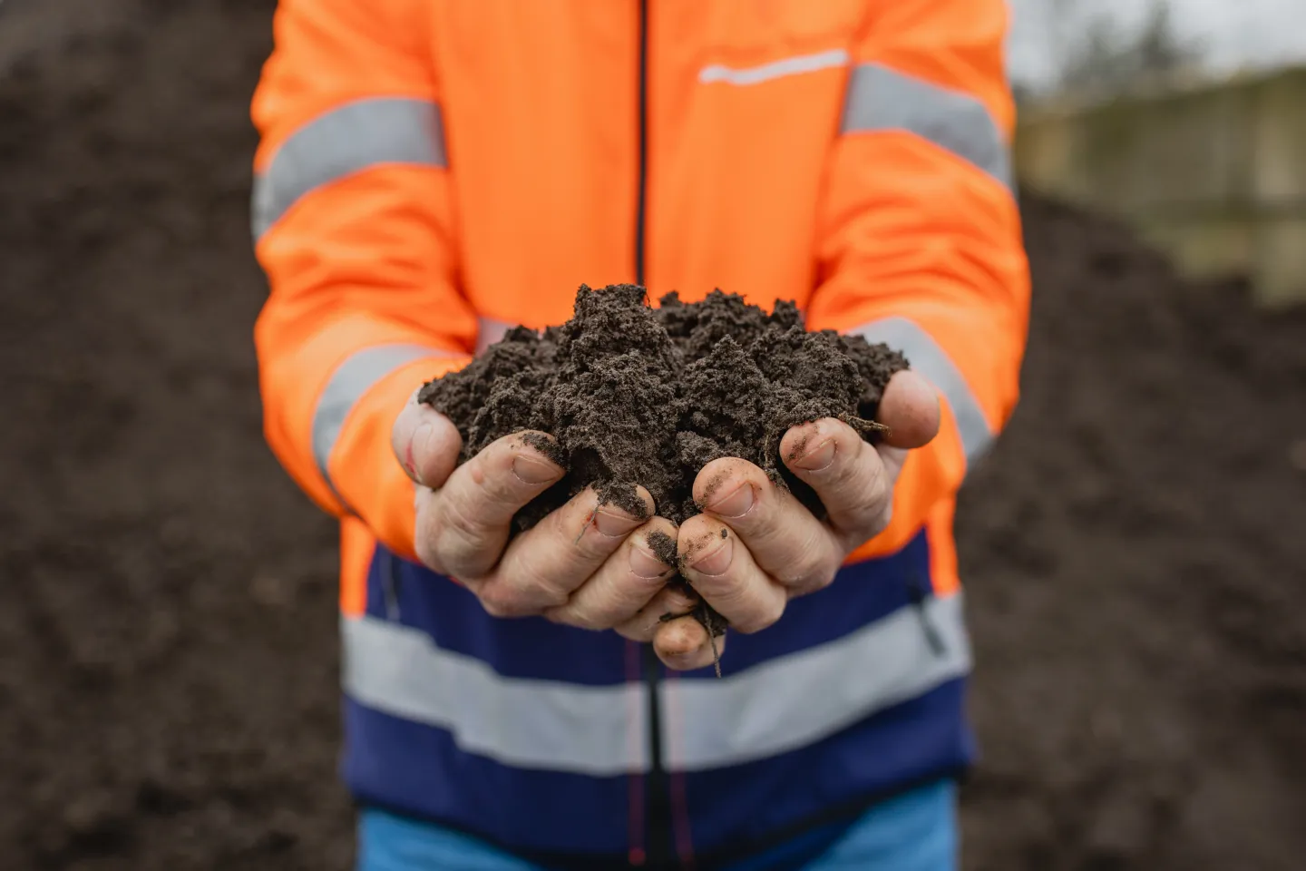 Handen naar voren gestoken met daarin een bergje compost