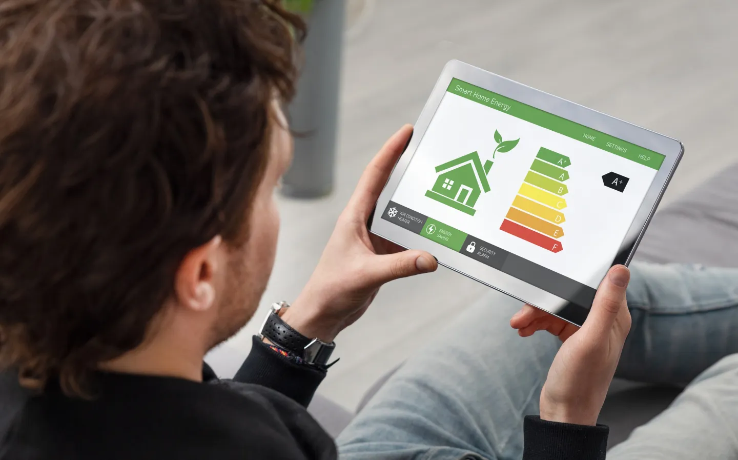 Persoon kijkt op een tablet met daarop een afbeelding van een huisje en energielabels