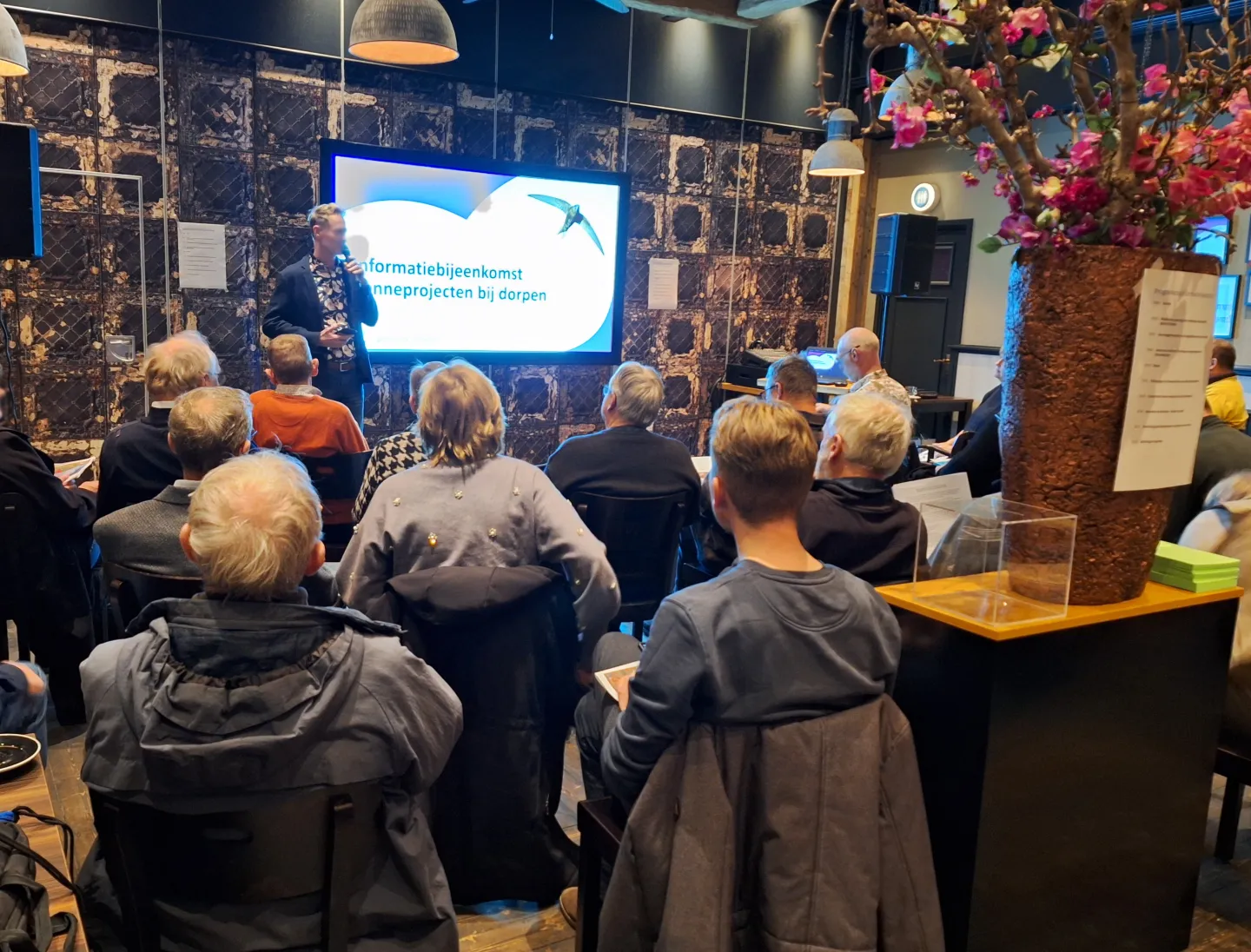Een presentator spreekt voor een groep mensen